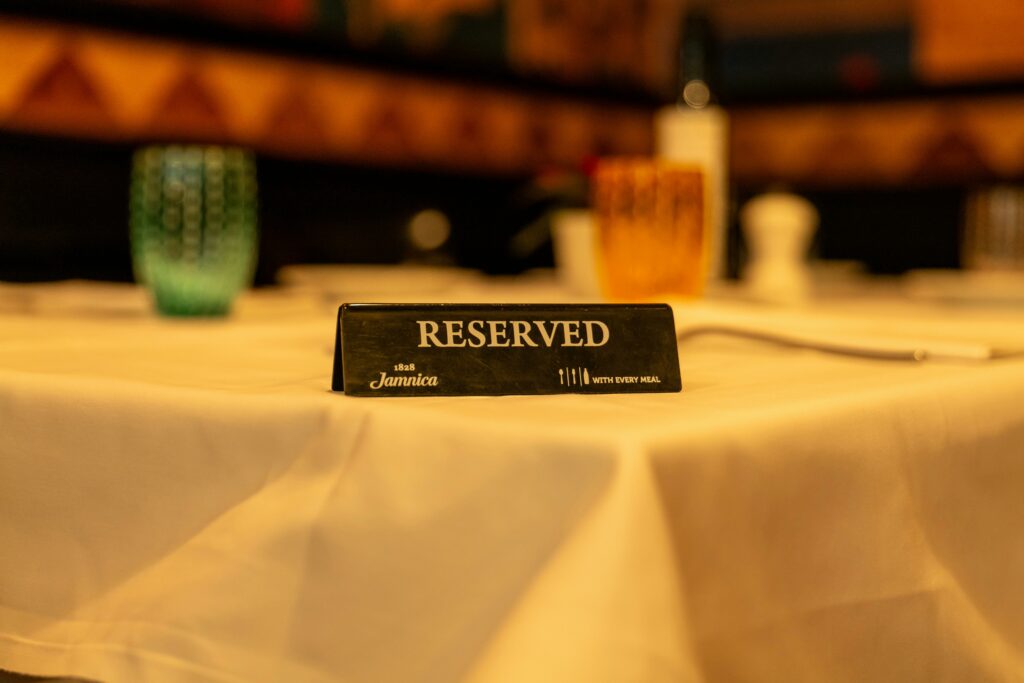 Close-up of a reserved sign on a white tablecloth in a dimly lit restaurant setting.