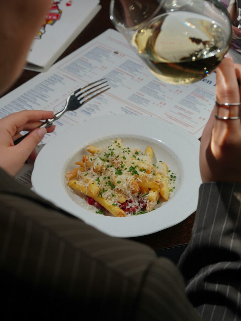 A detailed close-up of a gourmet pasta dish paired with white wine, set beside a dining menu.